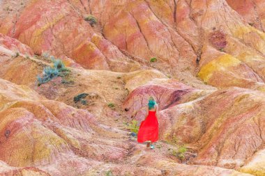 Kırgızistan'da Kanyon Masalı. Kum tepelere karşı kırmızı elbiseli bir kız. Issyk-Kul Gölü bölgesinde doğa.