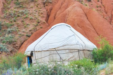 Kırgızistan'da Kanyon Masalı. Kumlu tepelerin arka planında beyaz yurt. Issyk-Kul Gölü bölgesinde doğa. Kırgız uyruklu Yurt.