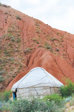 Kırgızistan'da Kanyon Masalı. Kumlu tepelerin arka planında beyaz yurt. Issyk-Kul Gölü bölgesinde doğa. Kırgız uyruklu Yurt.