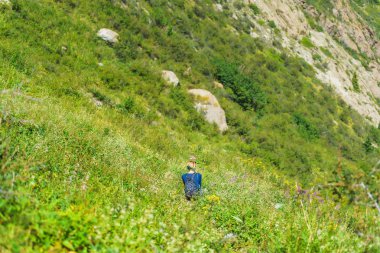 Barskoon Geçidi. Yamaçta oturan kız. Kırgızistan'da dinlenin. Issyk-Kul gölüne gezi.