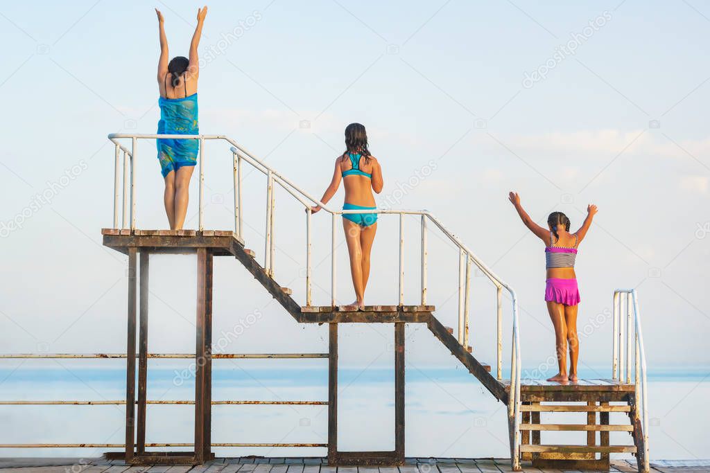 The girls are on a wooden pier.  Trip to Issyk Kul lake. Girls in colorful swimsuits. Rest in Kyrgyzstan.