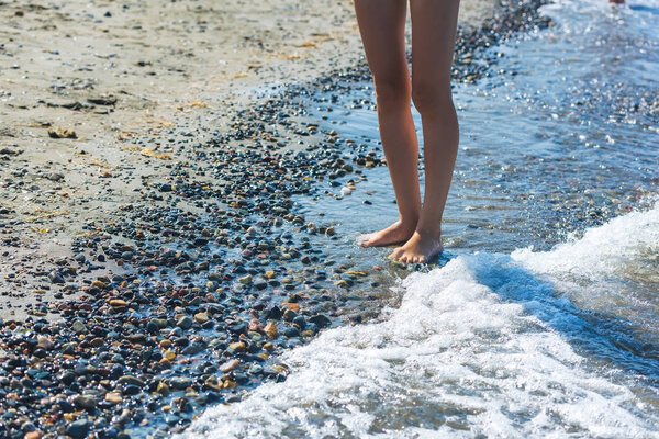 Девушка в купальнике идет по скалистому берегу. Красочные камни на пляже озера Иссык-Куль. Отдых в Кыргызстане. Мокрая галька
.