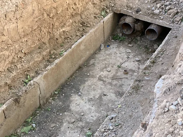 Replacement of heating pipes. Repair of pipes with drinking water. The texture of excavated earth. Metal pipe under the ground.