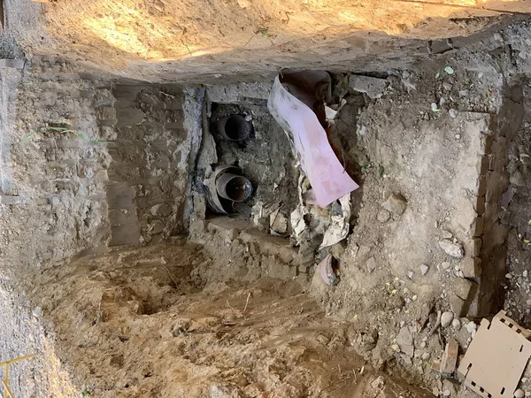 Replacement of heating pipes. Repair of pipes with drinking water. The texture of excavated earth. Metal pipe under the ground.