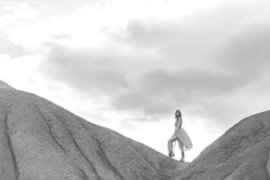 Kırgızistan'daki kanyon peri masalında kırmızı elbiseli kız. Kırgızistan'ın İsyk-Kul bölgesinin turuncu-sarı-kırmızı dağlarında bir kadın. Çok renkli dağların arka planda güzel kız. Orta Asya'da çok renkli kayalıklar.