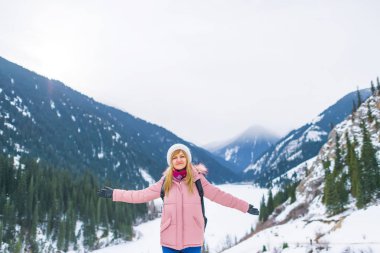 Kışın donmuş bir gölde dağlarda kız. Kazakistan'da dağlarda kış gölü Kolsay turist kız. Almat bölgesinde Kolsay Dağı Gölü.