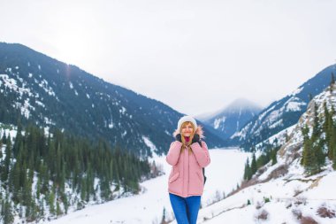 Kışın donmuş bir gölde dağlarda kız. Kazakistan'da dağlarda kış gölü Kolsay turist kız. Almat bölgesinde Kolsay Dağı Gölü.