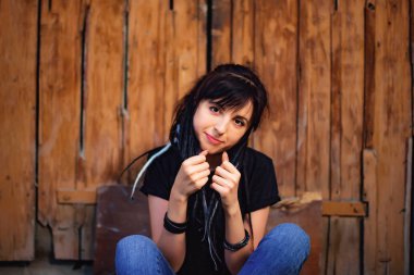 Ahşap arka planda siyah beyaz dreadlocks ile kız. Doğal dreadlocks ile kadın. Köyde ahşap kapı yakınında oturan güzel beyaz kız.