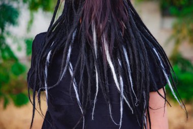 Bir kızın sırtındaki siyah ve beyaz dreadlocks. Arka görüş Kafasına siyah dreadlocks. Dokuma dreadlocks.