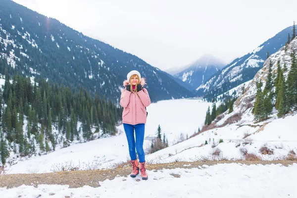 Girl in the mountains in winter on a frozen lake. Tourist girl on winter lake Kolsay in the mountains in Kazakhstan. Mountain lake Kolsay in the Almaty region.