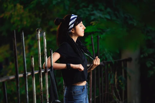 公園の黒と白のドレッドロックを持つ女の子 ドレッドロックの若い女性屋外の黒いTシャツとジーンズでヒッピースタイルの女の子モデル — ストック写真