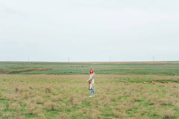 Girl with pink hair in the field. Woman model in a long cardigan in the steppe.