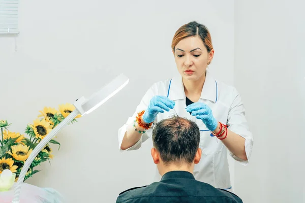 Trikolog bir kozmetolojistin ofisinde kel bir noktası olan genç bir adam. Saç ve baş mezoterapisi için hazırlanıyor. Erkeklerde saç dökülmesiyle mücadele etmek. Erkek tipi kellik için tedavi yöntemleri