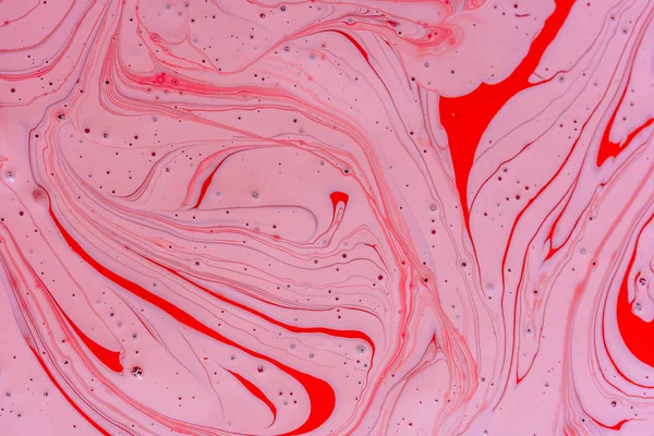 The mixing of the two liquid colors red and pink. Beautiful abstract pink red two color background. Coloring acrylic latex paint