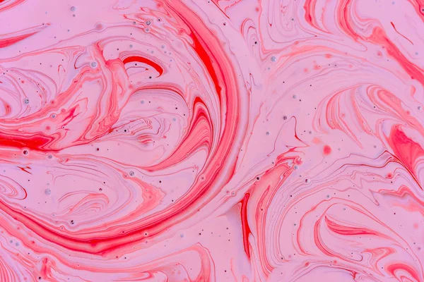 The mixing of the two liquid colors red and pink. Beautiful abstract pink red two color background. Coloring acrylic latex paint