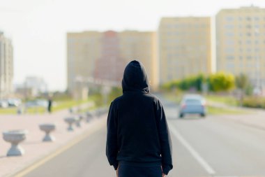 Koşudan önce ısınan kız. Atlet koşmaya hazırlanıyor. Çok katlı binaların arka planında üniformalı kadın.