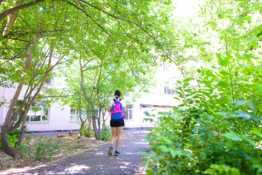 Kız pistte çalışan ışık çalışır. Renkli sırt çantası olan üniformalı bir kadın..