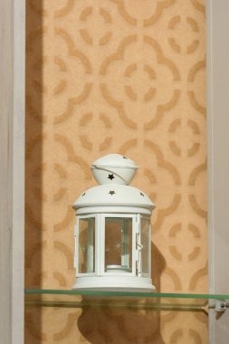 Metal fener mumluk. Dekoratif eleman. Beyaz bir mum çubuğu cam bir rafta duruyor.