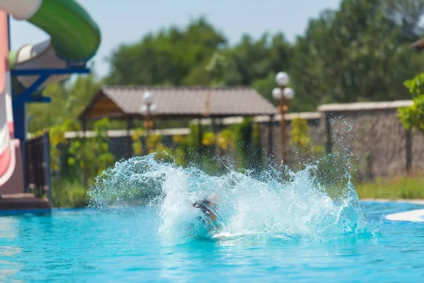 男はウォーターパークで滑り台を転がした プールの水の飛沫 ウォーターパークでの夏休み — ストック写真