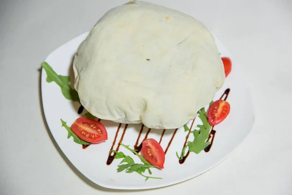 Vegetarian dish. Food without salt and oil. Dish of dough with arugula and tomatoes.