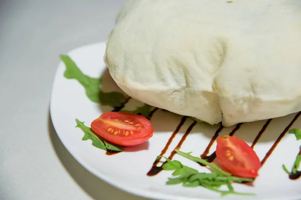 Vegetarian dish. Food without salt and oil. Dish of dough with arugula and tomatoes.