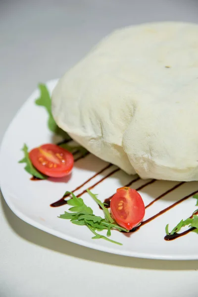 Vegetarian dish. Food without salt and oil. Dish of dough with arugula and tomatoes.