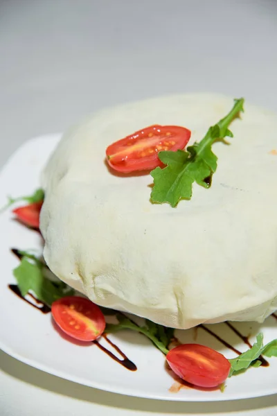 Vegetarian dish. Food without salt and oil. Dish of dough with arugula and tomatoes.