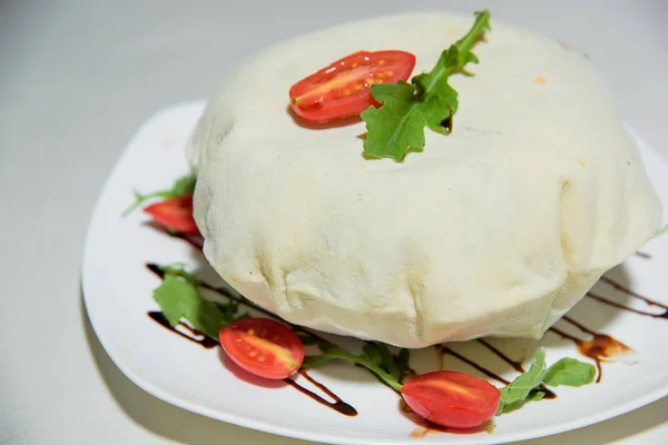 Vegetarian dish. Food without salt and oil. Dish of dough with arugula and tomatoes.