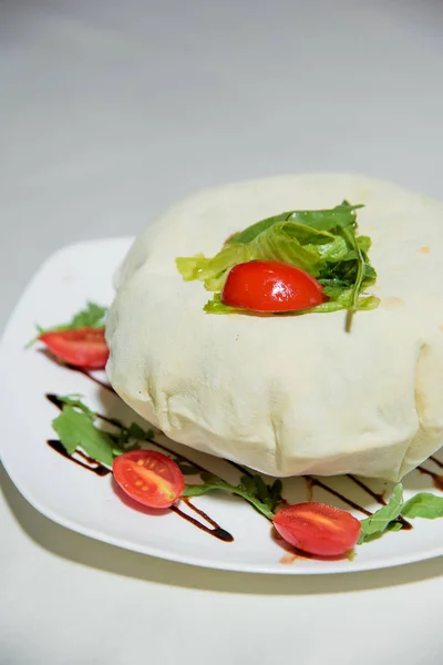 Vegetarian dish. Food without salt and oil. Dish of dough with arugula and tomatoes.