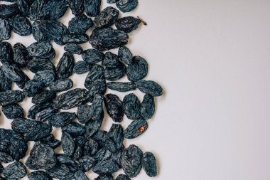 Beyaz arka planda siyah kuru üzüm. Siyah kurutulmuş üzüm deseni. Beyaz arka planda oryantal kurutulmuş meyveler.
