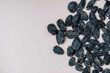 Beyaz arka planda siyah kuru üzüm. Siyah kurutulmuş üzüm deseni. Beyaz arka planda oryantal kurutulmuş meyveler.