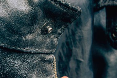Siyah ceketli metal yuvarlak çiviler. Giysiler üzerinde dekoratif unsurlar. Yıpranmış deri ceketin dokusu.