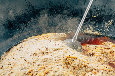 Büyük bir kazanda gerçek Özbek pilavı. Taşkent'teki pilav merkezi. Özbekistan'da ulusal yemekler pişirmek. Kazanda etli pilav. Geleneksel pilav pişirme