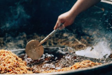 Büyük bir kazanda gerçek Özbek pilavı. Taşkent'teki pilav merkezi. Özbekistan'da ulusal yemekler pişirmek. Kazanda etli pilav. Geleneksel pilav pişirme