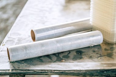 Yemek, bir kafede masanın üzerinde bir rulo sarın. Paket gıda için tek kullanımlık plastik sofra ve gıda filmi. Bir yığın gıda kabı.