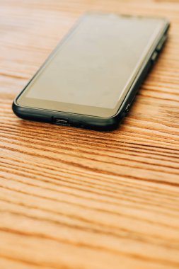 Akıllı telefon ahşap bir masanın üzerinde. Ahşap yüzey dokusu. Siyah dokunmatik telefon.