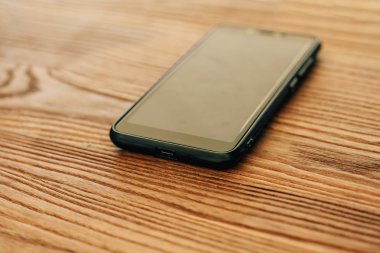 Akıllı telefon ahşap bir masanın üzerinde. Ahşap yüzey dokusu. Siyah dokunmatik telefon.