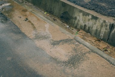 Islak asfalt. Asfalt yüzeyinde çamur var. Yoldaki su birikintileri.