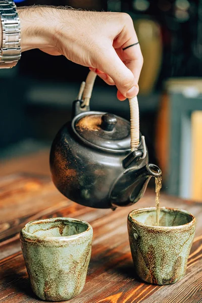 A teapot of tea with mugs on a wooden background. Dishes for Chinese-style tea. Tea in an Asian cafe. Old Antiquarian Tableware for Hot Drinks