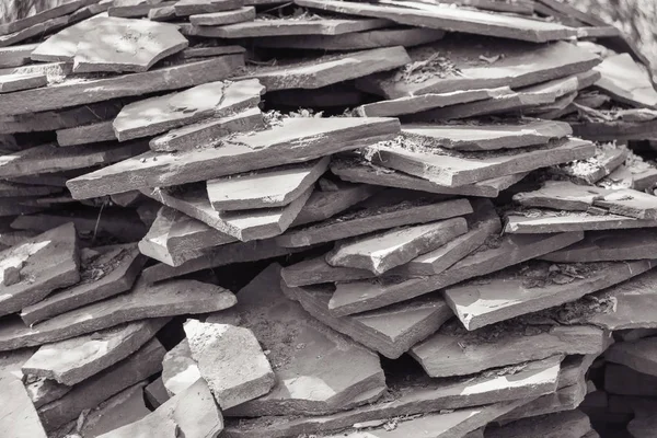 Decorative stone tiles lying on the green grass. Building material. Natural stone tiles. Black and white photo.