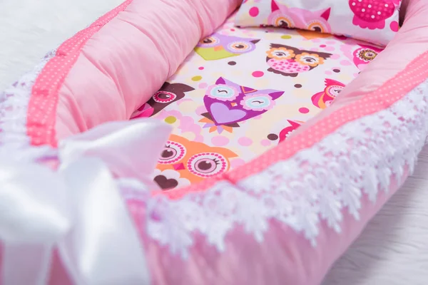 Mattress cocoon and pillow for newborns. Bedding for a baby cot. The mattress is pink.