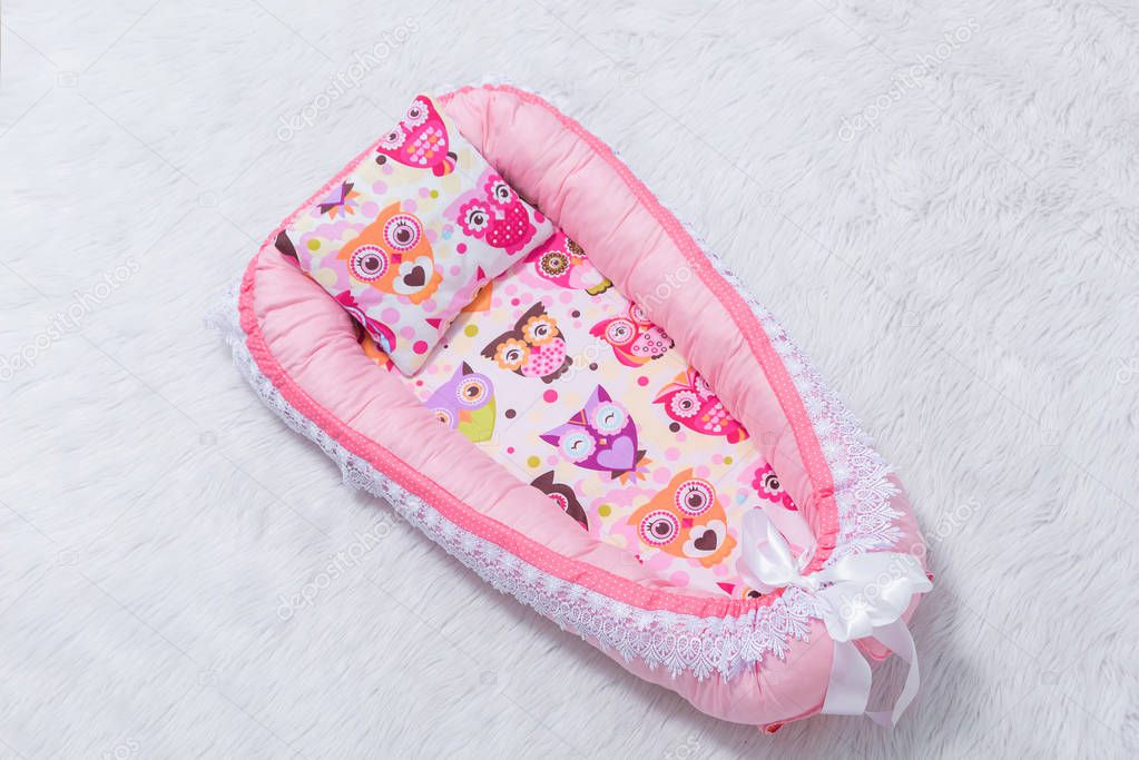 Mattress cocoon and pillow for newborns. Bedding for a baby cot. The mattress is pink.