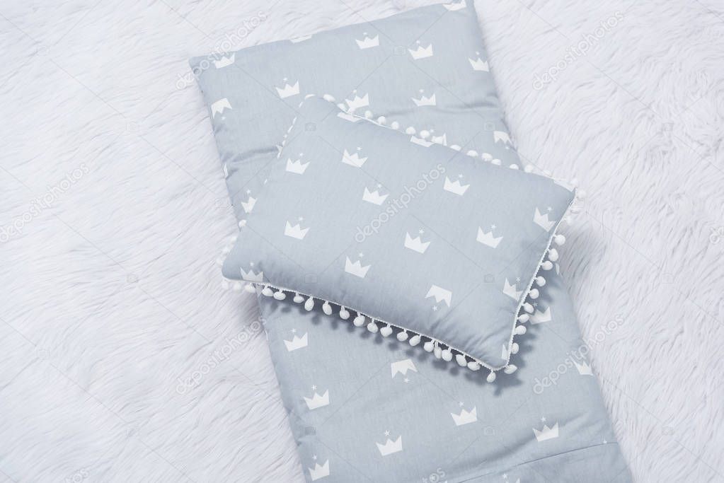 Decorative children's mattress and pillow for newborns. Bedding for a baby cot. The mattress is grey.