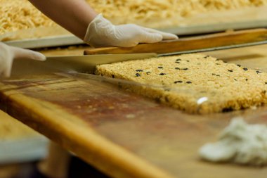 Kuru üzüm ile tatlı dilimlenmiş hamur. Şeker fabrikasında tatlı chak-chak pişirme. Hamur tatlı tatlı.