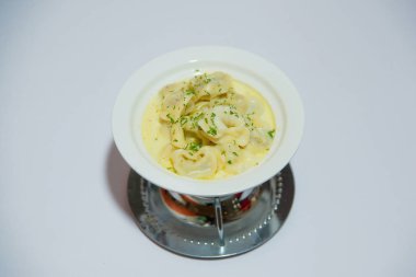 Otlar ile krem sosu köfte. Bir tabak hamur ve et. Beyaz plakalı köfte.