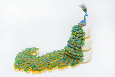 Üç katlı beyaz kek. Bir kuş tavuskuşu figürü ile süslenmiş tatlı pasta. Beyaz buzlanma içinde pasta stand üzerinde.