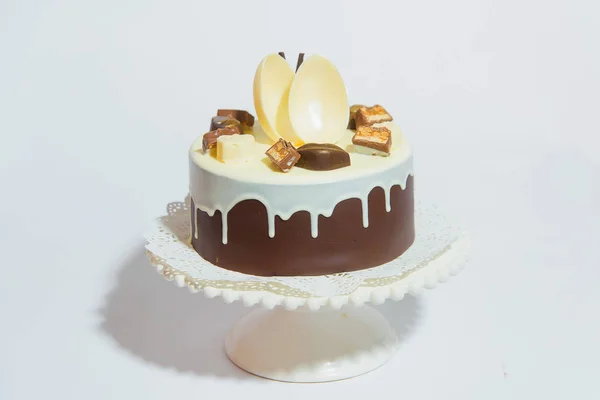 Chocolate cake with a round figure. Sweet confectionery decorated with chocolate pieces. The cake with chocolate icing is on the stand.