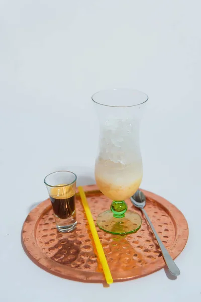 Cold coffee drink with a plastic tube. A soft drink stands on a tray. Preparation of cold coffee.