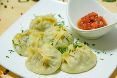 Bir tabak hamur ve et. Sos ile et yemeği. Hafif bir masaya karşı bir tabak yiyecek.