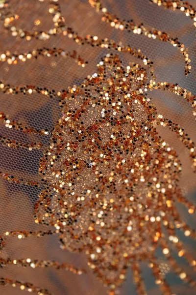 Fabric with gold sequins. The texture of the shiny material. Decorative fabric trimmed with gold sequins.
